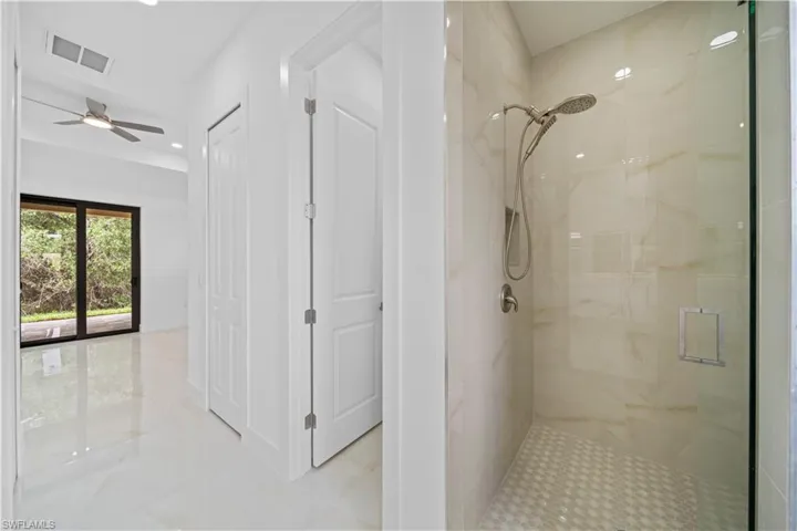 Walk-in shower featuring light-toned tile, brushed nickel fixtures, a glass enclosure, and a built-in shower niche