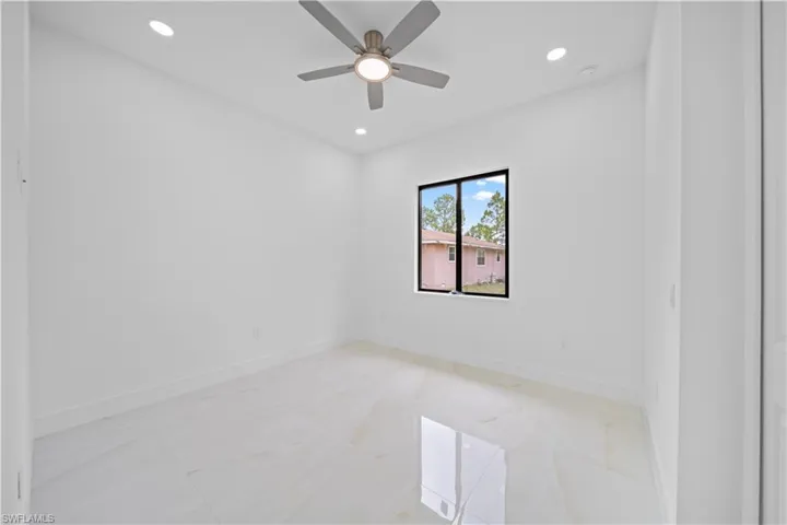 Bright room featuring a ceiling fan with integrated lighting, recessed lighting, and large format tile flooring