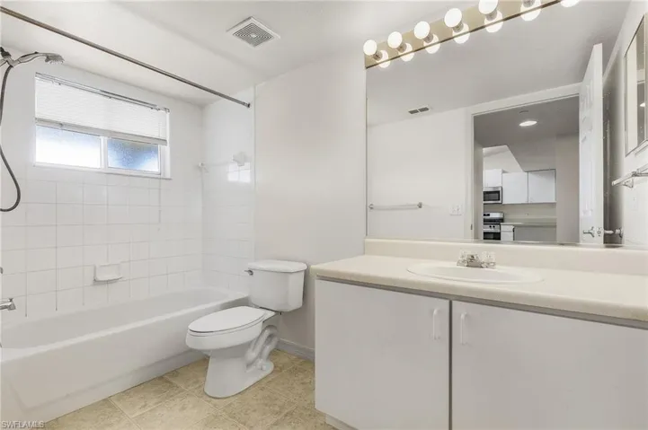 Full bathroom with tiled shower / bath combo, vanity, tile patterned floors, and toilet