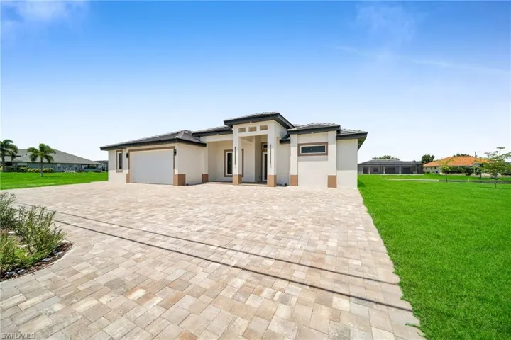 Prairie-style home with an attached garage, a tiled roof, decorative driveway, stucco siding, and a front lawn