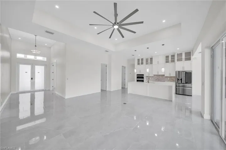 Unfurnished living room with marble finish floor, a high ceiling, visible vents, and a tray ceiling