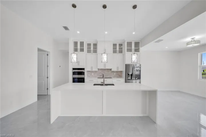 Kitchen featuring visible vents, decorative backsplash, appliances with stainless steel finishes, white cabinetry, and a sink