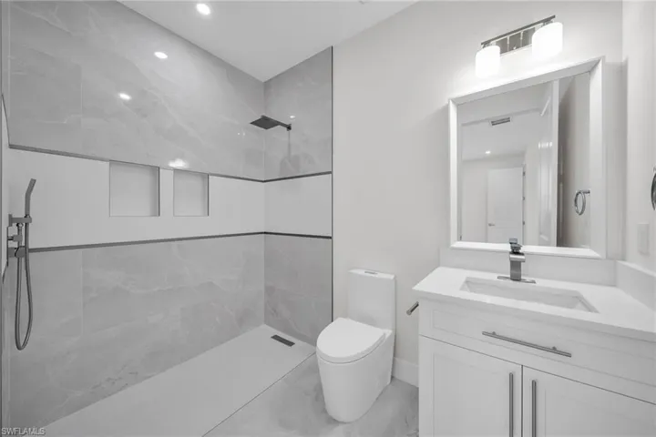 Full bathroom with toilet, tiled shower, and vanity