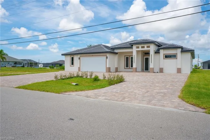 Prairie-style home featuring a garage, a front yard, decorative driveway, and stucco siding
