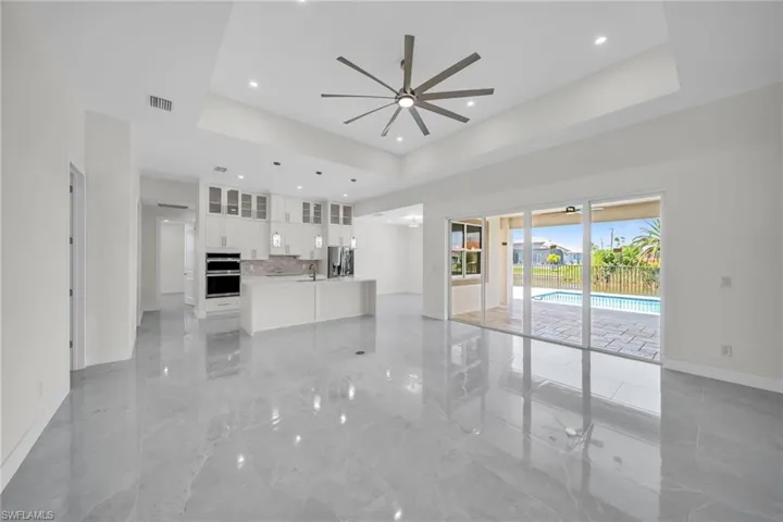 Unfurnished living room with a raised ceiling, visible vents, ceiling fan, and marble finish floor