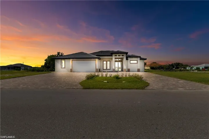 Prairie-style home with a lawn, driveway, stucco siding, and a garage