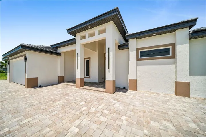 View of exterior entry featuring an attached garage, a patio area, a tiled roof, and stucco siding