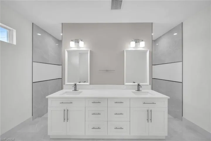 Bathroom featuring double vanity, marble finish floor, visible vents, and a sink