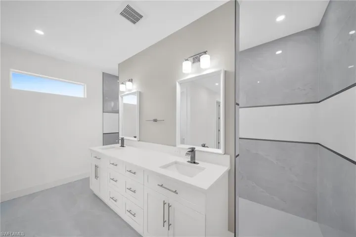 Bathroom featuring double vanity, a sink, visible vents, and baseboards