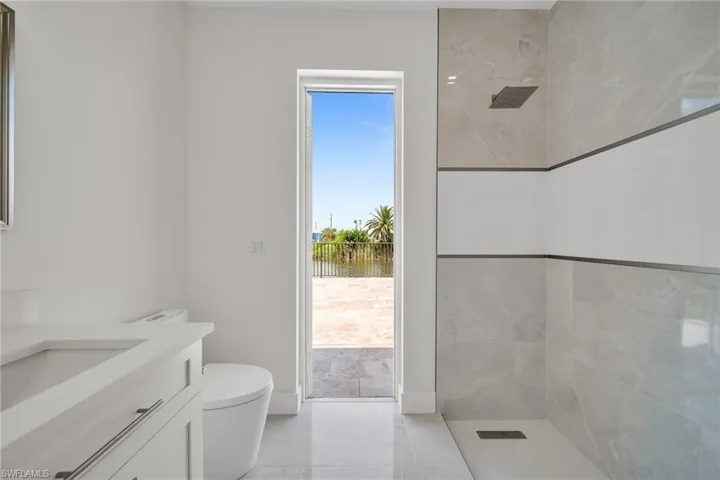 Bathroom with tiled shower, vanity, and toilet