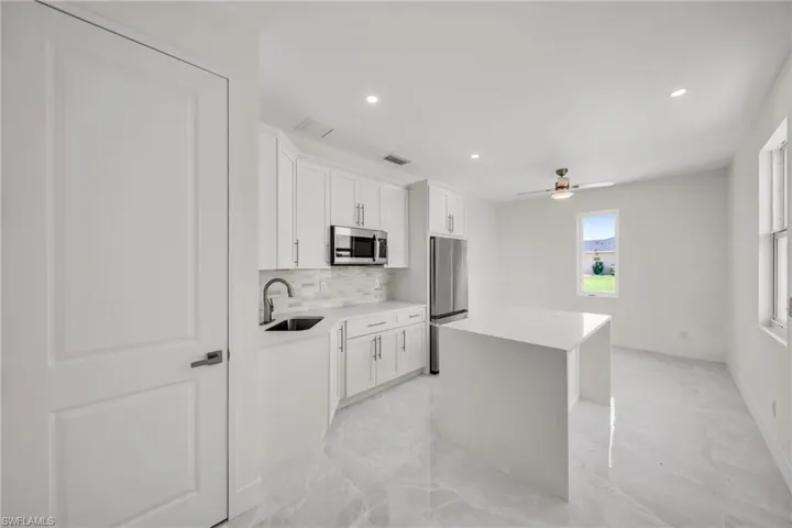 Kitchen featuring marble finish floor, tasteful backsplash, appliances with stainless steel finishes, a kitchen island, and a sink