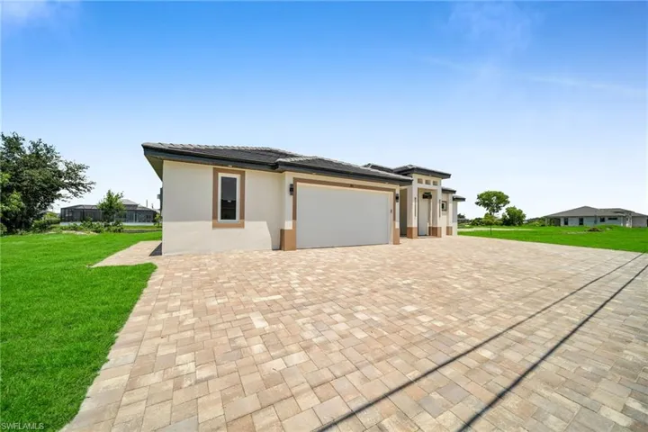 Prairie-style house with a tiled roof, an attached garage, decorative driveway, a front yard, and stucco siding