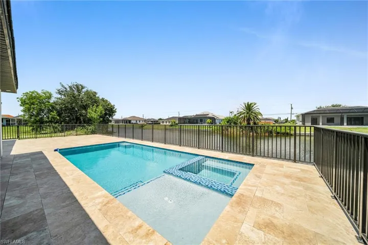 View of pool with a patio area, a pool with connected hot tub, and fence