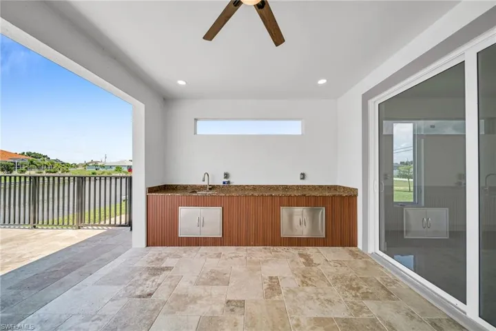 View of patio / terrace featuring exterior kitchen, ceiling fan, a sink, and fence