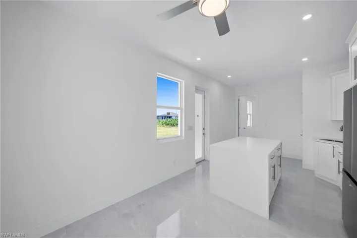 Kitchen featuring a center island, recessed lighting, light countertops, a ceiling fan, and white cabinets