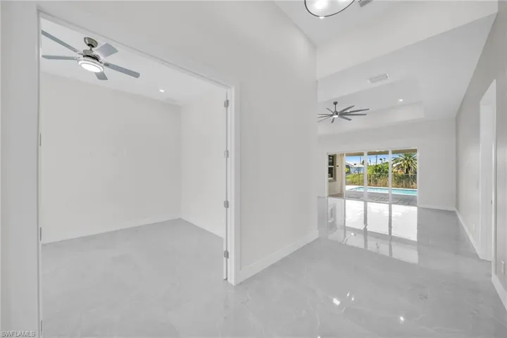 Unfurnished room featuring visible vents, baseboards, a ceiling fan, marble finish floor, and a tray ceiling