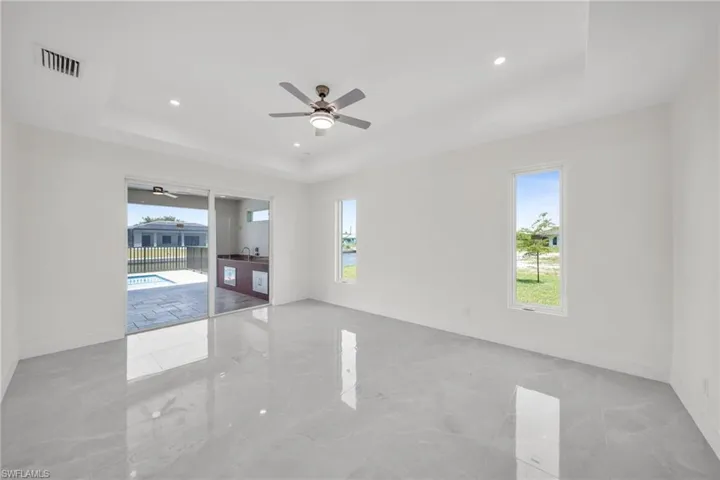 Unfurnished room featuring a ceiling fan, a wealth of natural light, a raised ceiling, and visible vents