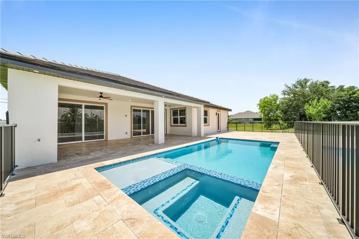 View of pool featuring a pool with connected hot tub, a patio area, ceiling fan, and fence