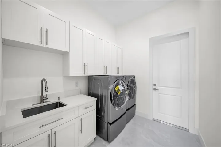 Washroom with cabinet space, baseboards, marble finish floor, washer and dryer, and a sink