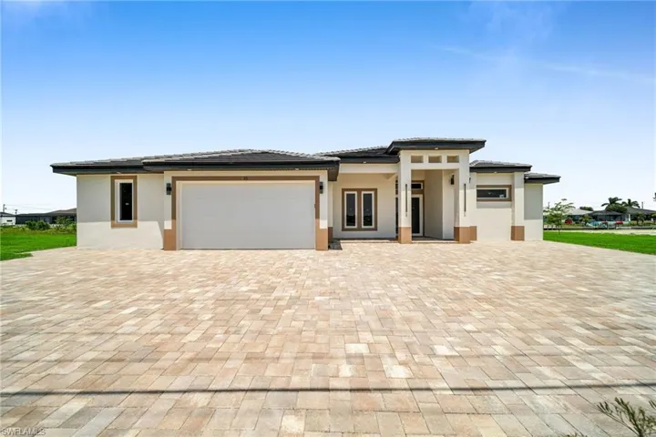 Prairie-style home featuring an attached garage, decorative driveway, and stucco siding