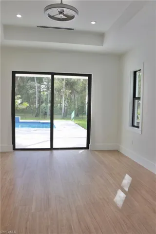 Unfurnished room with light wood-style flooring, a raised ceiling, and recessed lighting