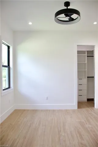 Unfurnished bedroom featuring a walk in closet, light wood-type flooring, recessed lighting, and a ceiling fan