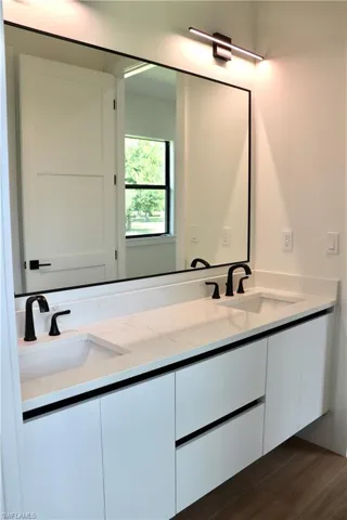 Full bathroom featuring double vanity and dark wood-type flooring