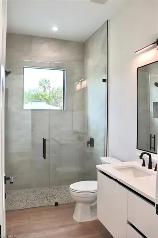 Bathroom with vanity, a stall shower, light wood-style floors, and recessed lighting