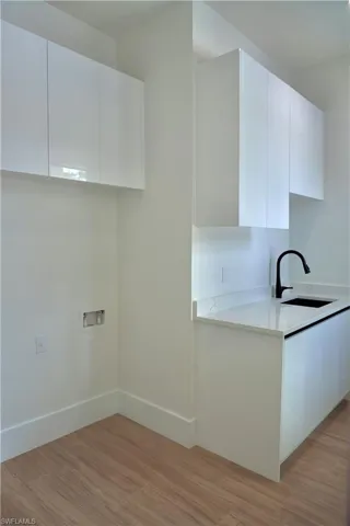 Washroom with light wood-type flooring, cabinet space, and hookup for a washing machine