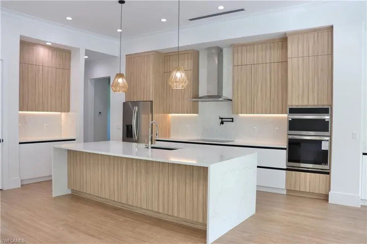 Kitchen with modern cabinets, light brown cabinets, backsplash, pendant lighting, and recessed lighting