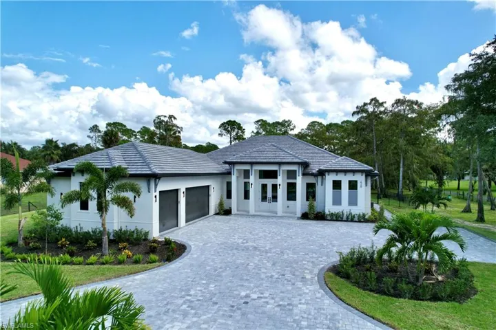 View of front of house featuring decorative driveway, an attached garage, and stucco siding