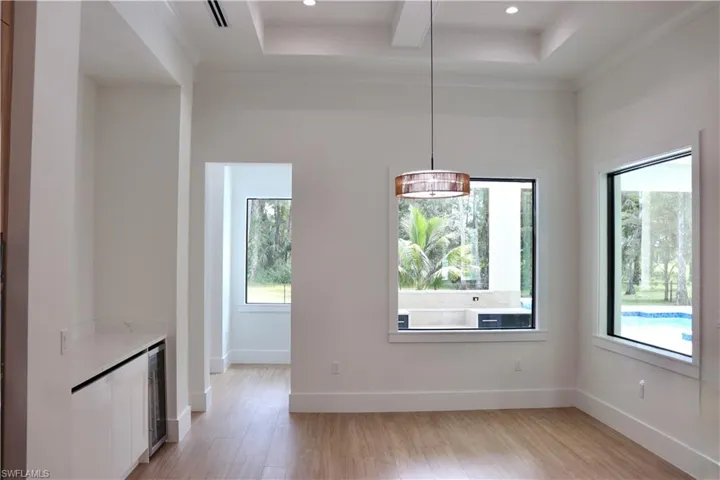 Unfurnished dining area with light wood-style flooring, recessed lighting, beverage cooler, and ornamental molding