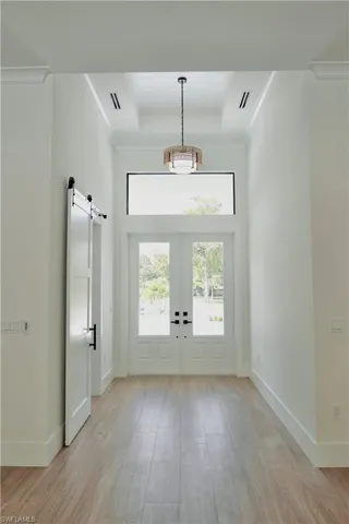 Entryway featuring a barn door, wood finished floors, french doors, ornamental molding, and a high ceiling
