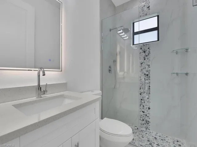 Bathroom with vanity, tiled shower, and toilet