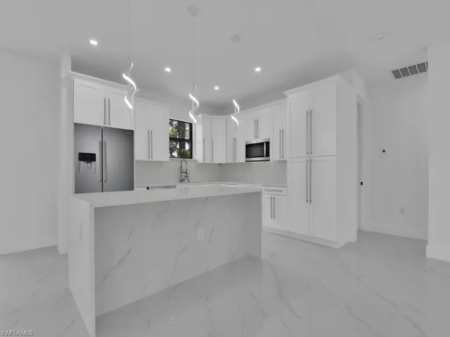 Kitchen featuring white cabinetry, light tile patterned floors, and stainless steel appliances