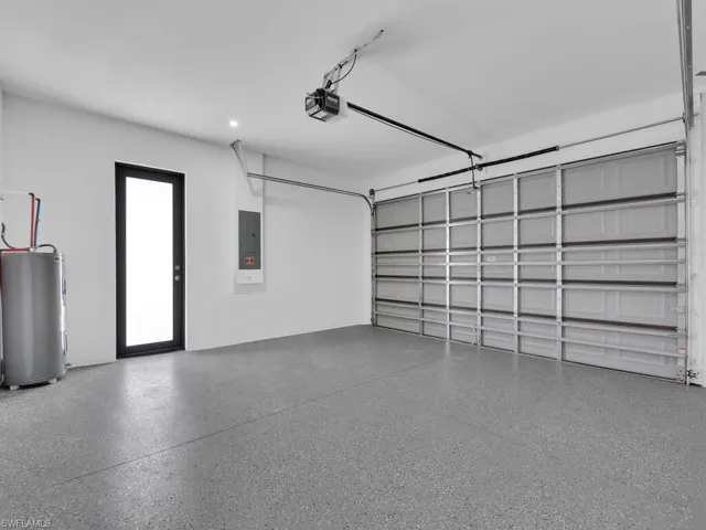 Garage with electric panel, a garage door opener, and water heater