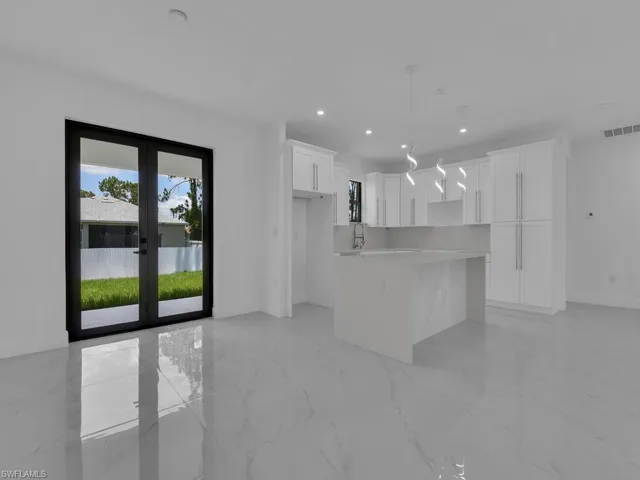 Kitchen with white cabinets, light tile patterned floors, french doors, and a kitchen island