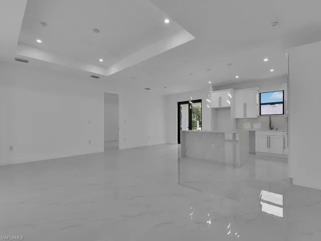 Unfurnished living room with a raised ceiling and light tile patterned floors
