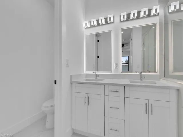 Bathroom with tile patterned floors, toilet, and dual bowl vanity
