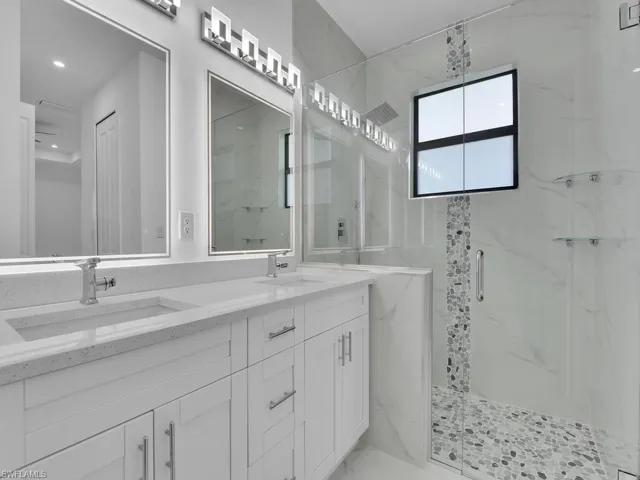 Bathroom featuring a shower with shower door and dual bowl vanity