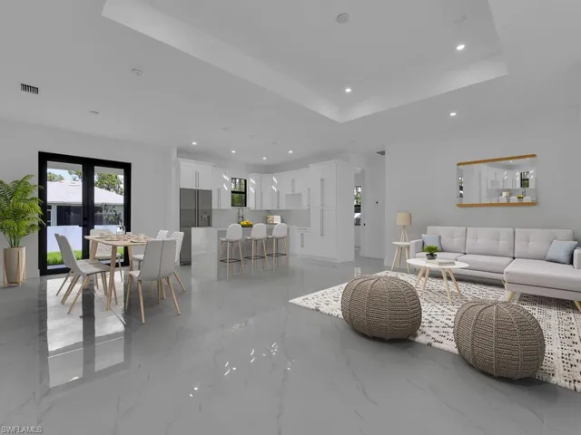Living room featuring french doors, a raised ceiling, and light tile patterned floors