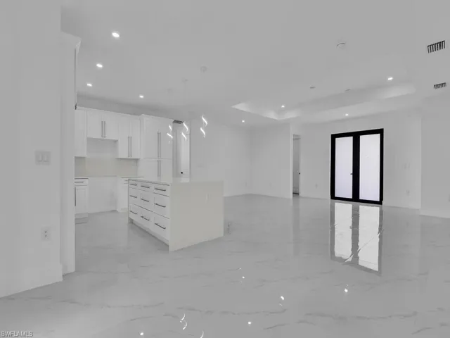 Kitchen featuring white cabinets, a center island, light tile patterned floors, and a tray ceiling
