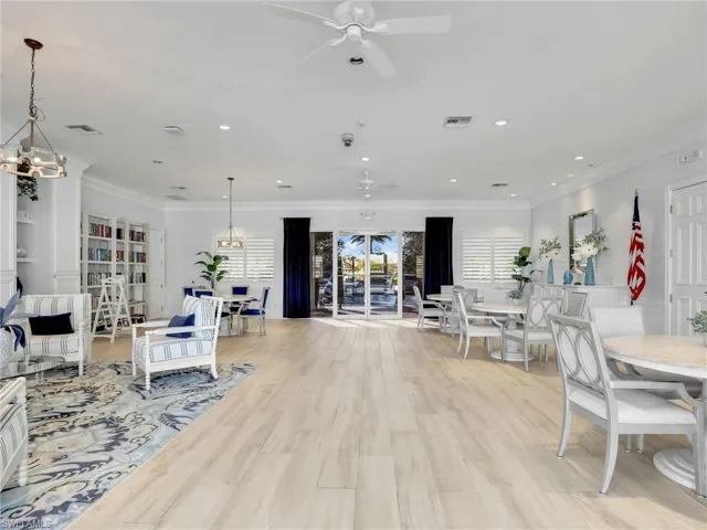 Living area featuring ornamental molding, light wood-style flooring, hanging lights, and ceiling fan