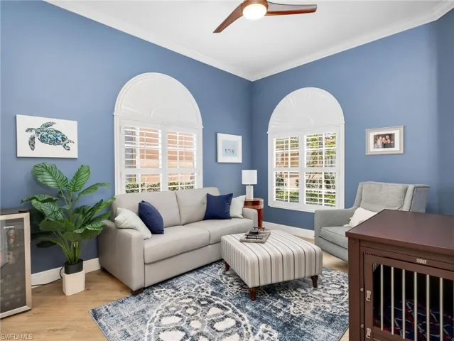 Living room with wine cooler, a ceiling fan, wood finished floors, and crown molding