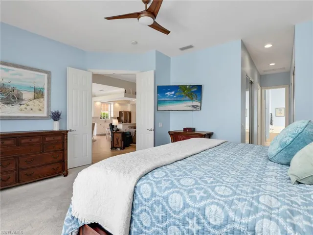 Bedroom with a ceiling fan, light carpet, ensuite bath, stainless steel refrigerator with ice dispenser, and recessed lighting