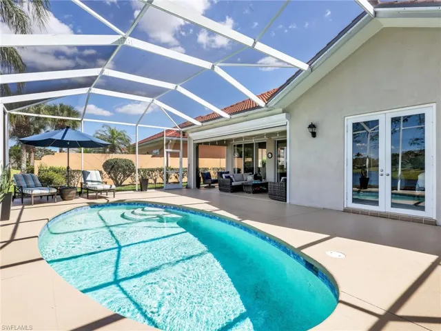 View of pool featuring patio surround, a sunroom, outdoor lounge area, and glass enclosure