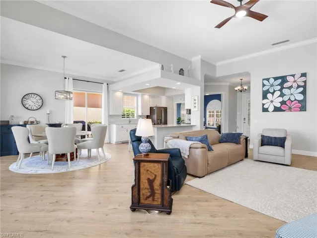 Living area featuring hanging lights, ornamental molding, light wood-type flooring, and ceiling fan