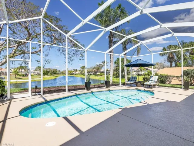 Swimming pool with a sunroom, glass enclosure, a water view, and a patio