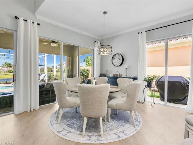 Dining room with crown molding, light wood-style flooring, ceiling fan, and hanging lights