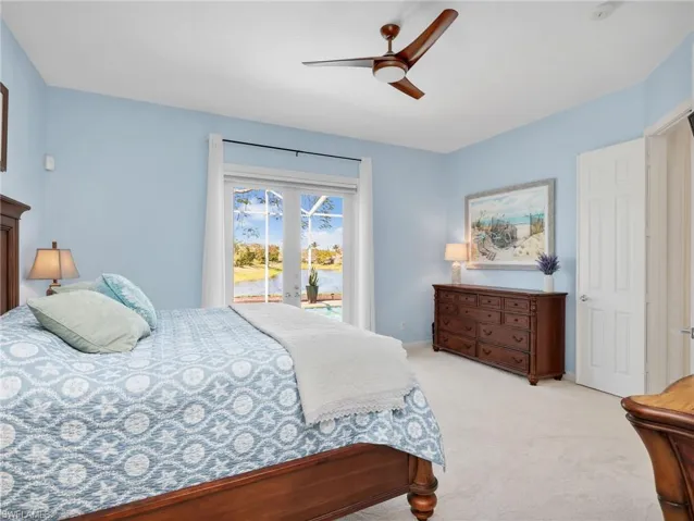 Carpeted bedroom featuring access to outside, ceiling fan, and a water view